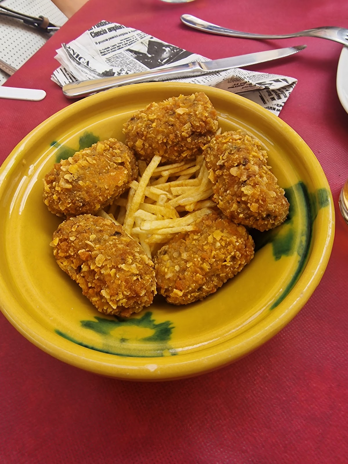 Plato de croquetas doradas y patatas fritas